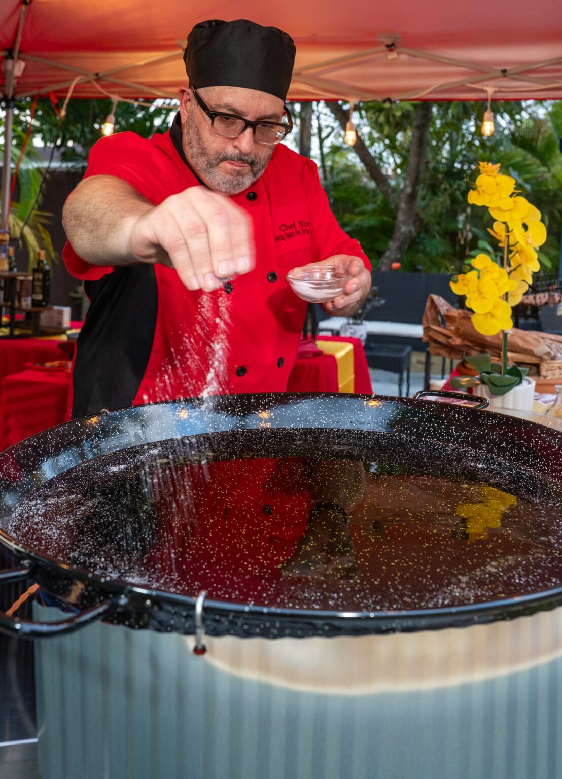 Chef Nino seasoning the paella pan at a backyard event