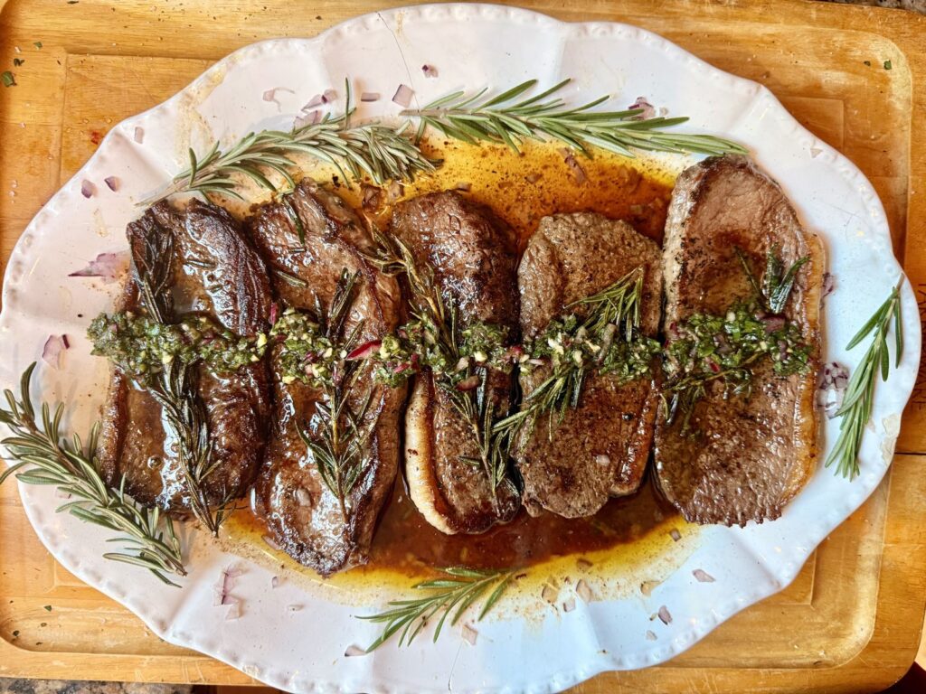 Sliced beef steaks with green chimichurri and fresh rosemary by Chef Nino