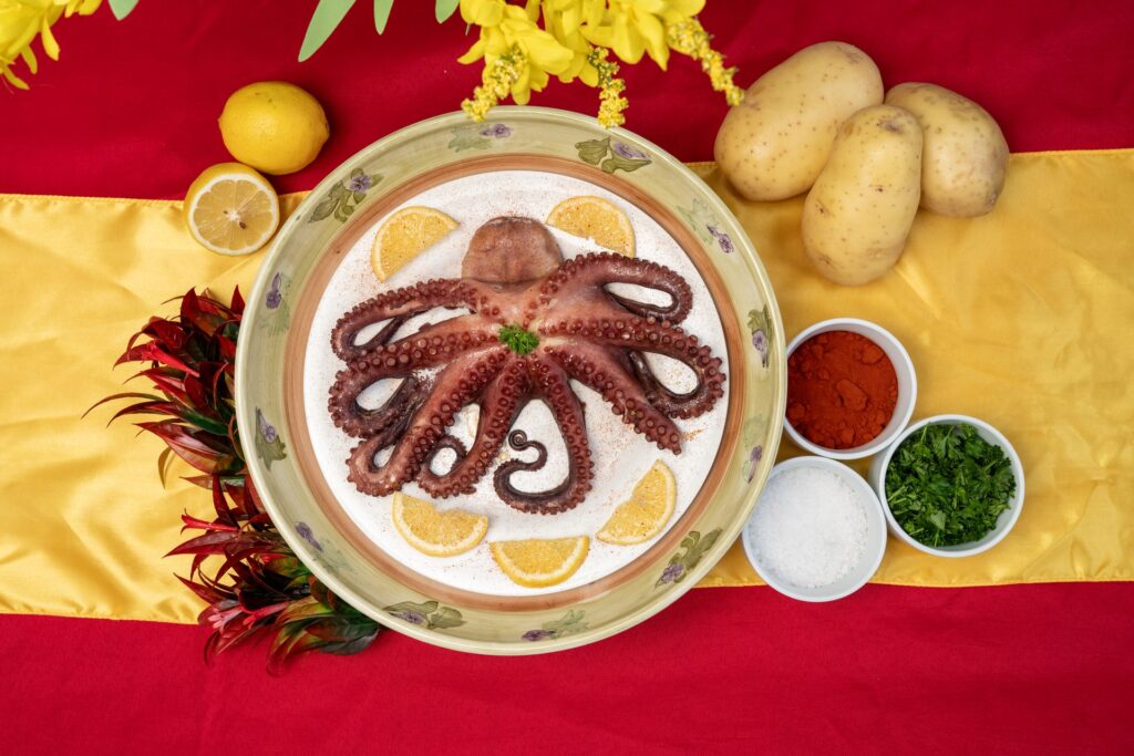 Whole Galician octopus on a Spanish-flag table with potatoes and pimentón